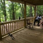 Guests relaxing on a wooded porch near the water during spring at The Oaks RV Park in Andalusia, Alabama