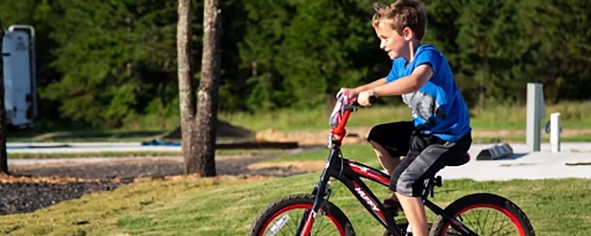 Child riding a bicycle through The Oaks RV Park during a spring camping trip in Andalusia, Alabama