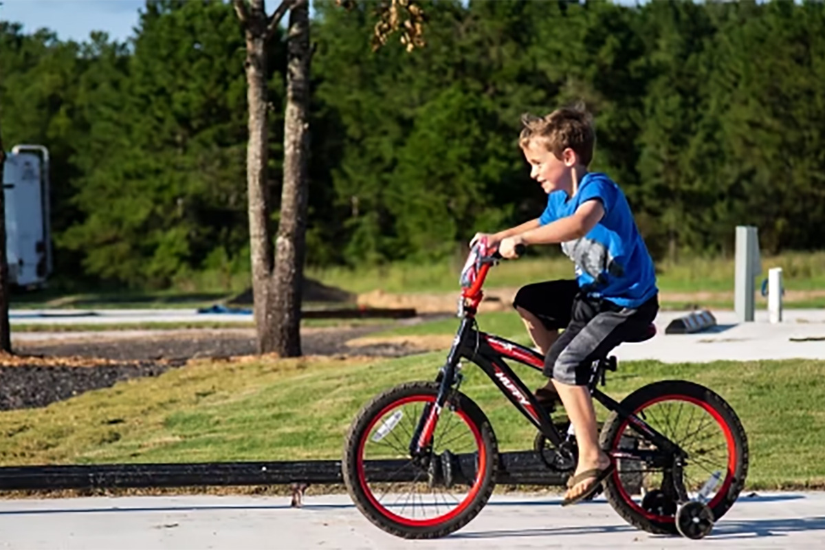 Child riding a bicycle through The Oaks RV Park during a spring camping trip in Andalusia, Alabama