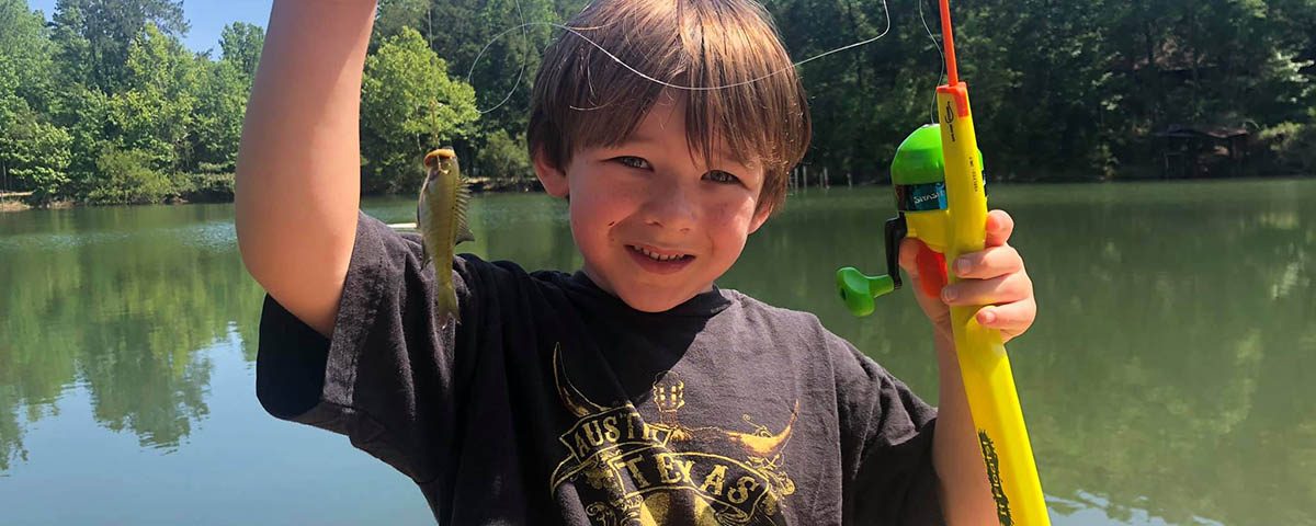 Child proudly holding his first fish while camping with family at The Oaks RV Park in Andalusia, Alabama