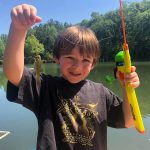 Child proudly holding his first fish while camping with family at The Oaks RV Park in Andalusia, Alabama
