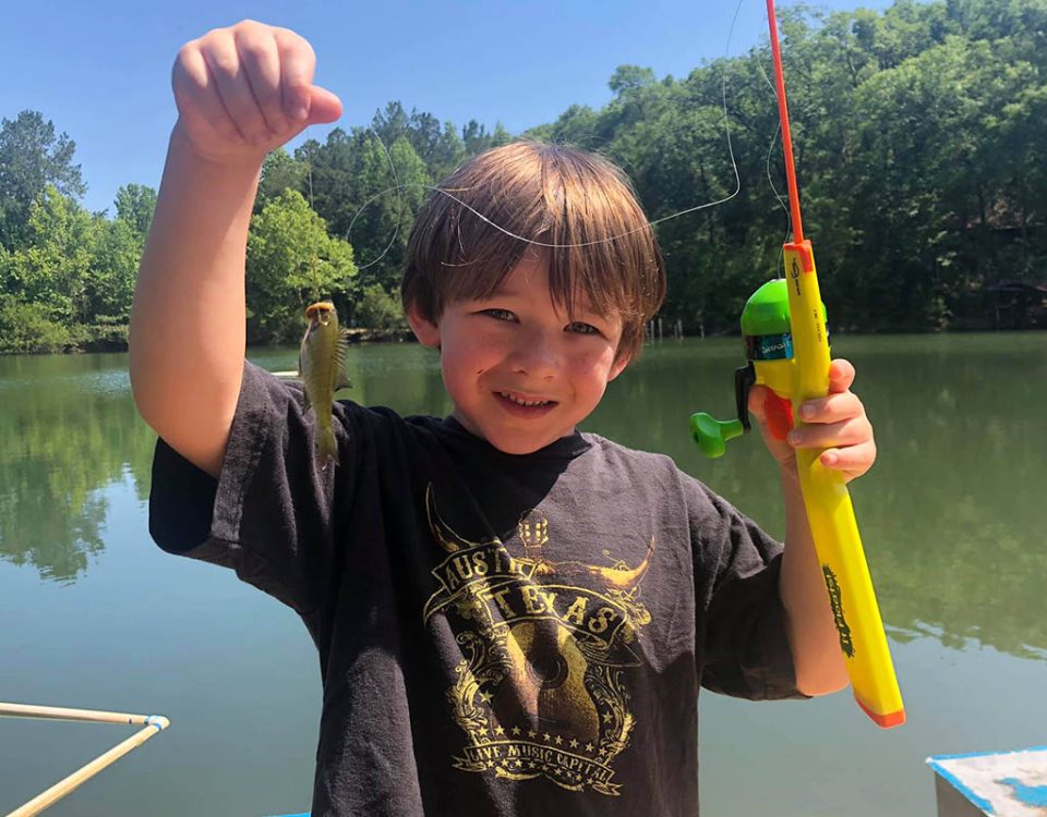 Child proudly holding his first fish while camping with family at The Oaks RV Park in Andalusia, Alabama