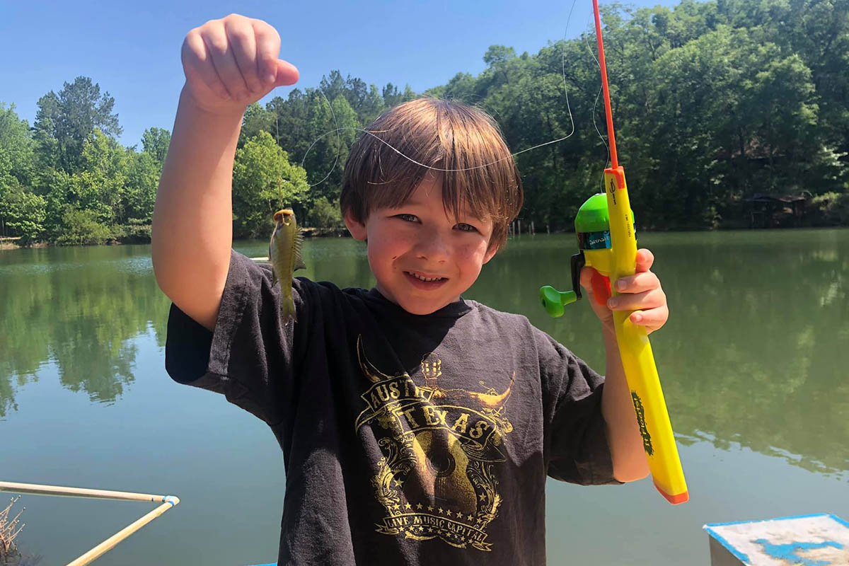 Child proudly holding his first fish while camping with family at The Oaks RV Park in Andalusia, Alabama