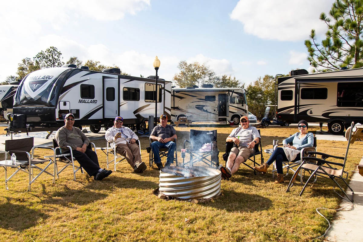 Working RV campers relaxing around a campfire during an extended stay at The Oaks RV Park in Andalusia, Alabama